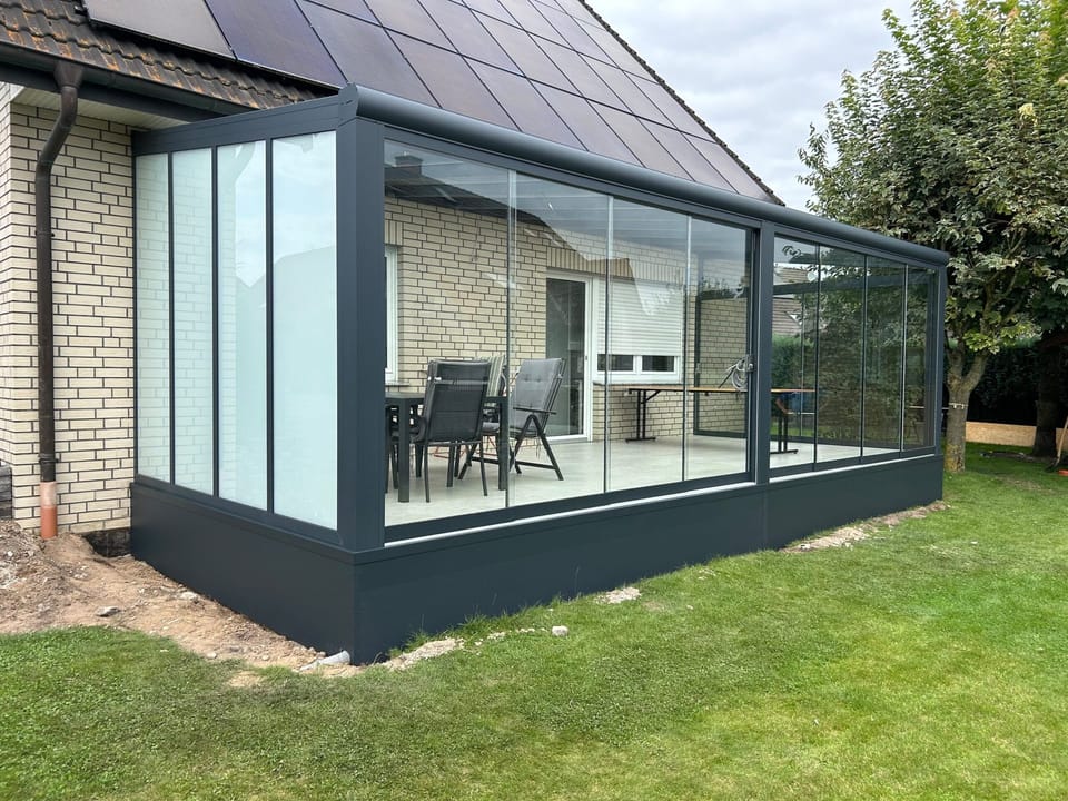 Wintergarten mit Glasschiebewänden an einem Klinkerhaus
