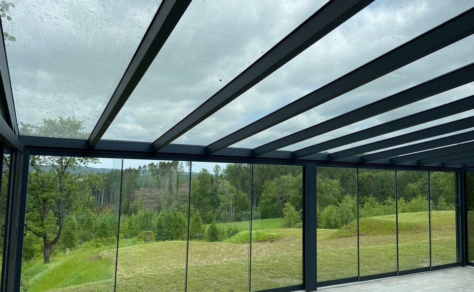 Blick aus einem verglasten Terrassendach in die Landschaft