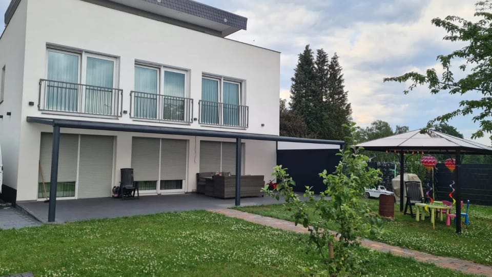 Terrassendach in Anthrazit an einem weißen Haus mit Garten